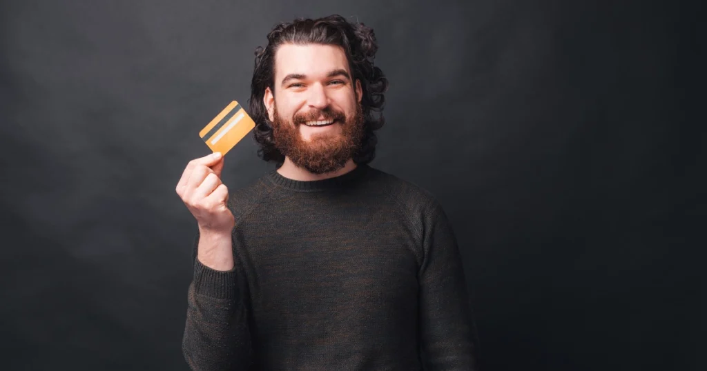 Close-up of a cheerful man presenting a yellow credit card, a metaphor for casino-style convenience on multicoin platforms.