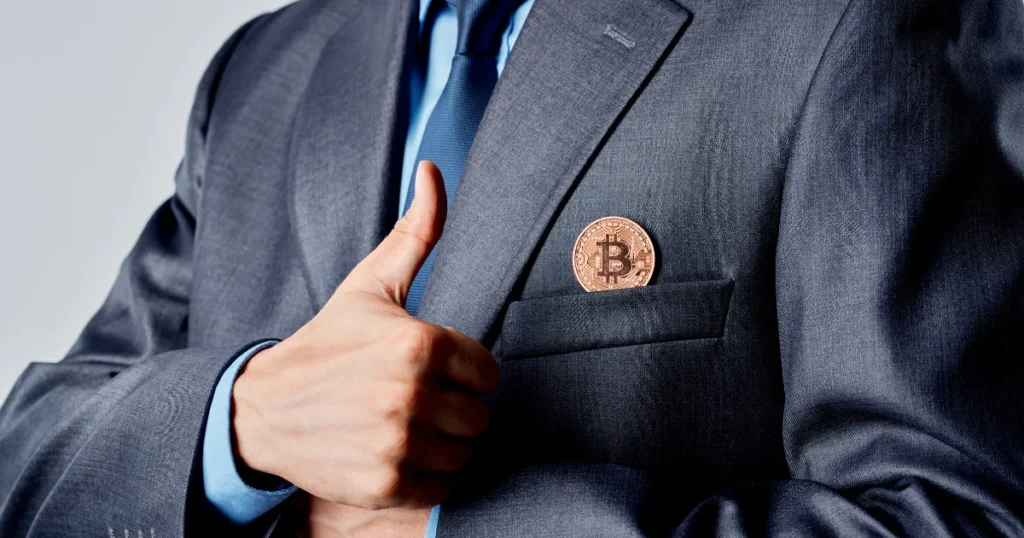 Person in a suit giving a thumbs up with a Bitcoin coin in the pocket, symbolizing owning your keys.